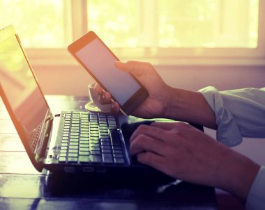  genç iş adamı meşgul onun laptop çalışma ve akıllı telefon kullanarak eller