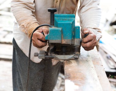 Marangoz elektrikli testereyle odun kesiyor. 