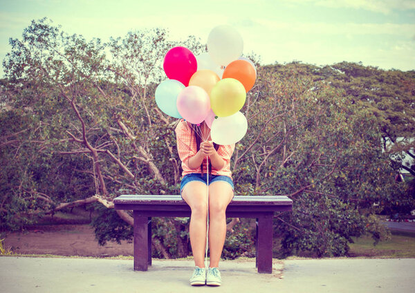 Happy young woman holding colorful balloons