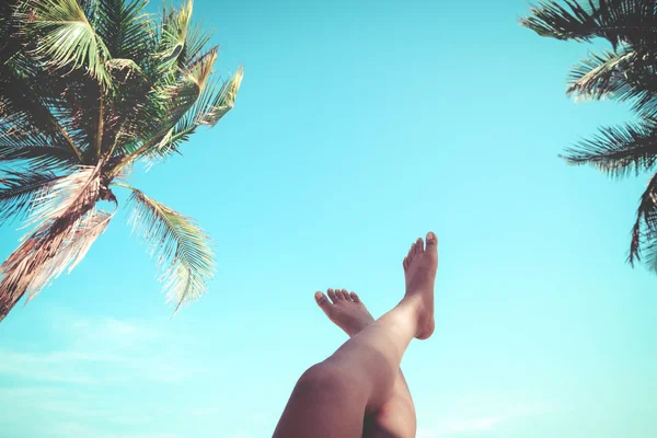 Jonge vrouwen liggend op een tropisch strand, ontspannen uitrekken slanke benen gelooid. — Stockfoto