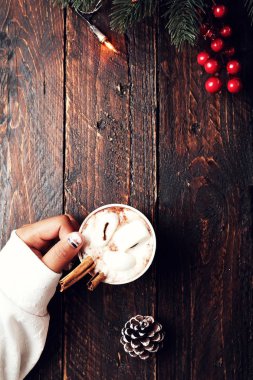 Sıcak çikolata içer ahşap masa üzerinde tutan kız el