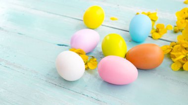 Yuvaya çiçek rustik ahşap plakalar arka plan üzerinde renkli Paskalya yumurtaları. Bahar mevsimi tatil. Vintage pastel renk tonu. Kompozisyon kadar kapatın.