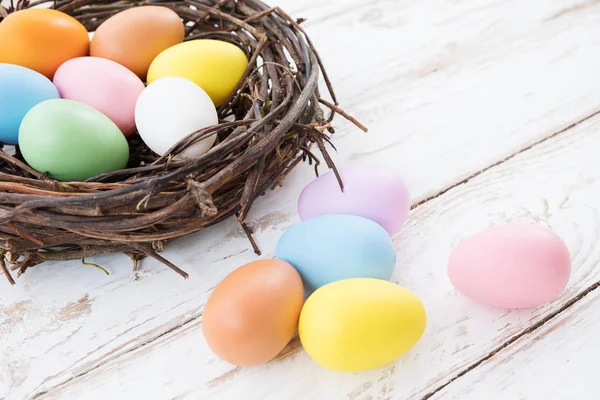 Yuvaya rustik ahşap plakalar arka plan üzerinde renkli Paskalya yumurtaları. Bahar mevsimi tatil. Vintage pastel renk tonu. Kompozisyon kadar kapatın.