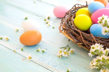 Yuvaya çiçek rustik ahşap plakalar arka plan üzerinde renkli Paskalya yumurtaları. Bahar mevsimi tatil. Vintage pastel renk tonu. Kompozisyon kadar kapatın.