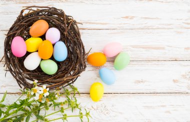 Yuva çiçek rustik ahşap plakalar arka planda beyaz boya ile renkli Paskalya yumurta. Bahar mevsimi tatil. Vintage renk tonu stili. Üstten Görünüm kompozisyon.