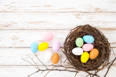 Renkli Paskalya yumurta yuva üzerinde rustik ahşap plakalar arka planda beyaz boya. Bahar mevsimi tatil. Vintage renk tonu stili. Üstten Görünüm kompozisyon.