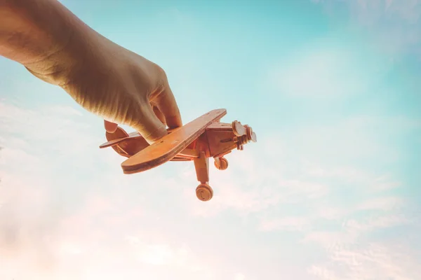Toy airplane in hand - an inspiration of travel and dreams. Vintage color filter effect.