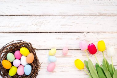 Yuvaya Lale çiçek rustik ahşap plakalar arka plan üzerinde renkli Paskalya yumurtaları. Bahar mevsimi tatil. Vintage pastel renk tonu. Üstten Görünüm kompozisyon.