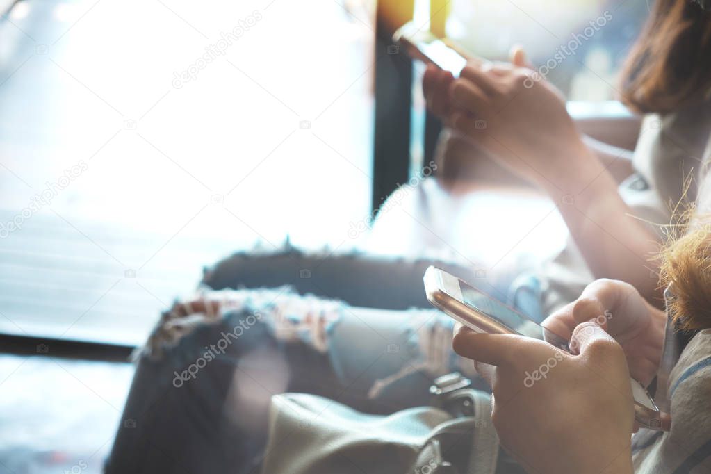 Two of  hipsters woman sitting on sofa holding en hands and using mobile phone. Coworking young women teamwork. business marketing online concept. retro film effect, blurred background