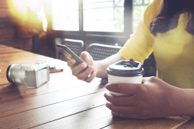 Eller kadın bir kafede tahta masada oturan akıllı telefonu kullanma. Asyalı kadınlar bir kafede - film renk tonu oturup rahatla.