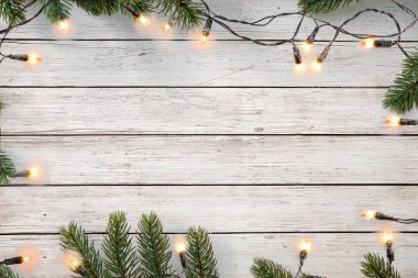 Noel ışıkları ampulü ve çam yaprakları beyaz tahta üzerinde, çerçeve sınır tasarımı. Mutlu Noeller ve yeni yıl tatili geçmişi. en üstteki görünüm.