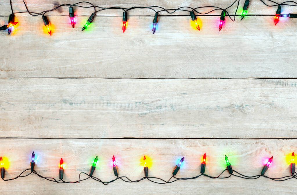 Christmas lights bulb frame decoration on white wood. Merry Christmas and New Year holiday background. top view