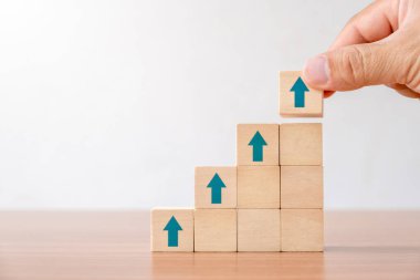 Business concept of ladder career path and growth success process. Hands of men arranging wood cube block stacking as step stair with arrow up.
