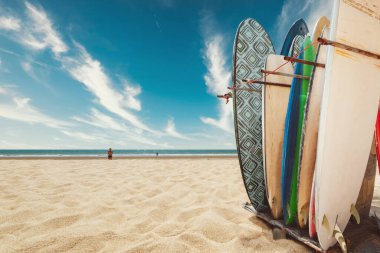 Yazın tropik sahilde sörf tahtası. Bulutlu beyaz kum manzarası, sakin deniz ve gökyüzü. Su sporları ve rahatlama. Klasik renk tonu