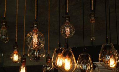 Çatı katı ve köy tarzında bir ev. Karanlıkta parlayan kaliteli, lüks bir ampul asılı. Retro filtre efekt biçimi. Tarihin ve modern hayatın karışımı.