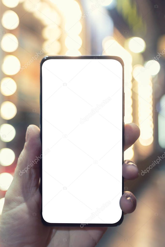 Phone in hand, close up, beautiful bokeh, white screen for text.
