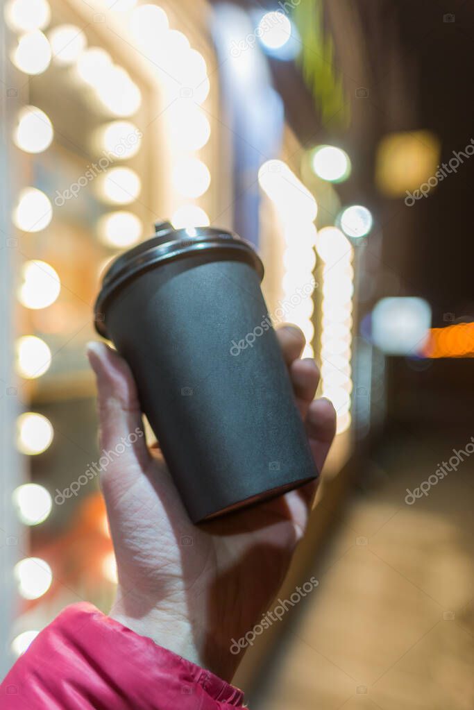 Coffee paper cup hand, background bokeh city lighting place text logo