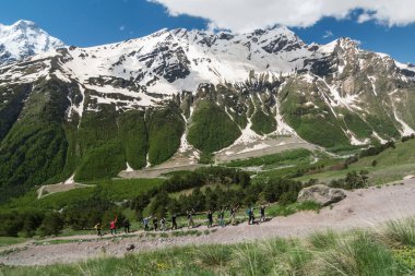 Kafkasya / Rusya - 02 / 06 / 2008 Dağcılık Grubu, Elbrus Dağı 'na tırmanmadan önce dağlarda iklim değiştirme programı. Turistler yüksek karlı dağ zirvelerinin arka planında fotoğraf çekiyorlar.