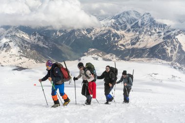 Kafkasya / Rusya - 02 / 06 / 2008 Dağcılık Grubu, Elbrus Dağı 'na tırmanmadan önce dağlarda iklim değiştirme programı. Turistler yüksek karlı dağ zirvelerinin arka planında fotoğraf çekiyorlar.