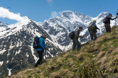 Kafkasya / Rusya - 02 / 06 / 2008 Dağcılık Grubu, Elbrus Dağı 'na tırmanmadan önce dağlarda iklim değiştirme programı. Turistler yüksek karlı dağ zirvelerinin arka planında fotoğraf çekiyorlar.