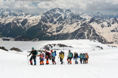 Kafkasya / Rusya - 02 / 06 / 2008 Dağcılık Grubu, Elbrus Dağı 'na tırmanmadan önce dağlarda iklim değiştirme programı. Turistler yüksek karlı dağ zirvelerinin arka planında fotoğraf çekiyorlar.