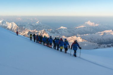 Kafkasya / Rusya - 22 / 06 / 2008 Dağcılık Grubu, Elbrus Dağı 'na tırmanmadan önce dağlarda iklim değiştirme programı. Turistler yüksek karlı dağ zirvelerinin arka planında fotoğraf çekiyorlar.