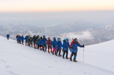 Caucasus / Russia - 07/31/2018 Group of climbers climbing mountain peaks.