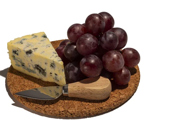 Mature Blue Stilton cheese with red grapes and knife  isolated on a white background