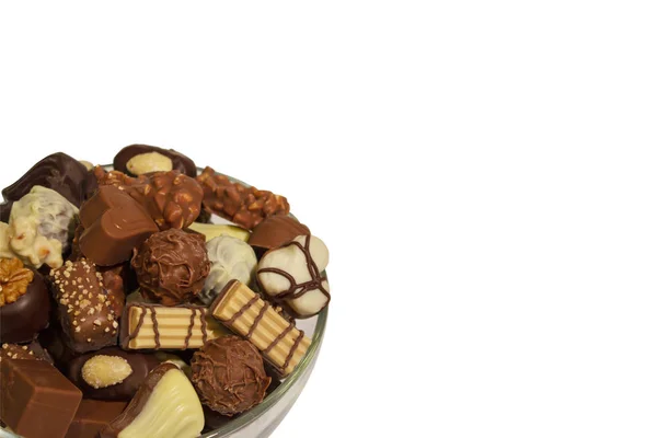 Various types of chocolate sweets arranged in a bowl on a white background
