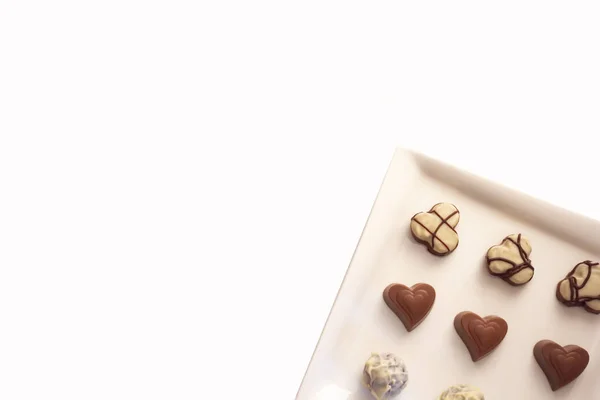 Various types of chocolate sweets arranged on a plate on a white background