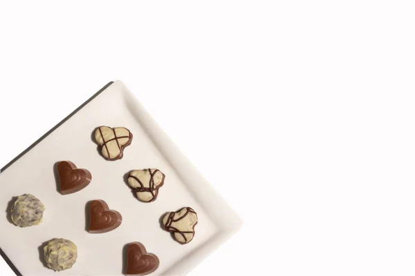 Various types of chocolate sweets arranged on a plate on a white background