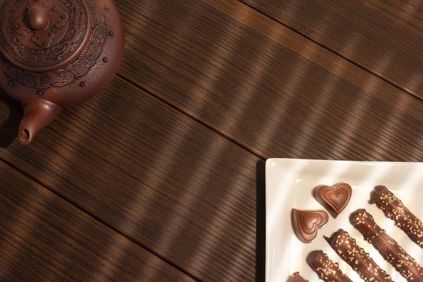Teekanne Aus Braunem Ton Schokoladenbonbons Auf Einem Teller Brauner Holzhintergrund — Stockfoto