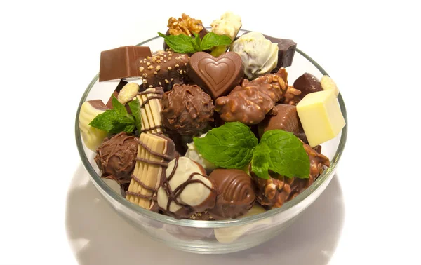 Various types of chocolate sweets arranged in a bowl on a white background