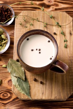 Tarçınlı Masala çayı, karanfil, baharatlı Hint çayı. Masala çayı. Ulusal mutfak, kakule, kekik, ahşap bir masada kara biber. Hint yemeği. Ulusal mutfak. Kahvaltı.