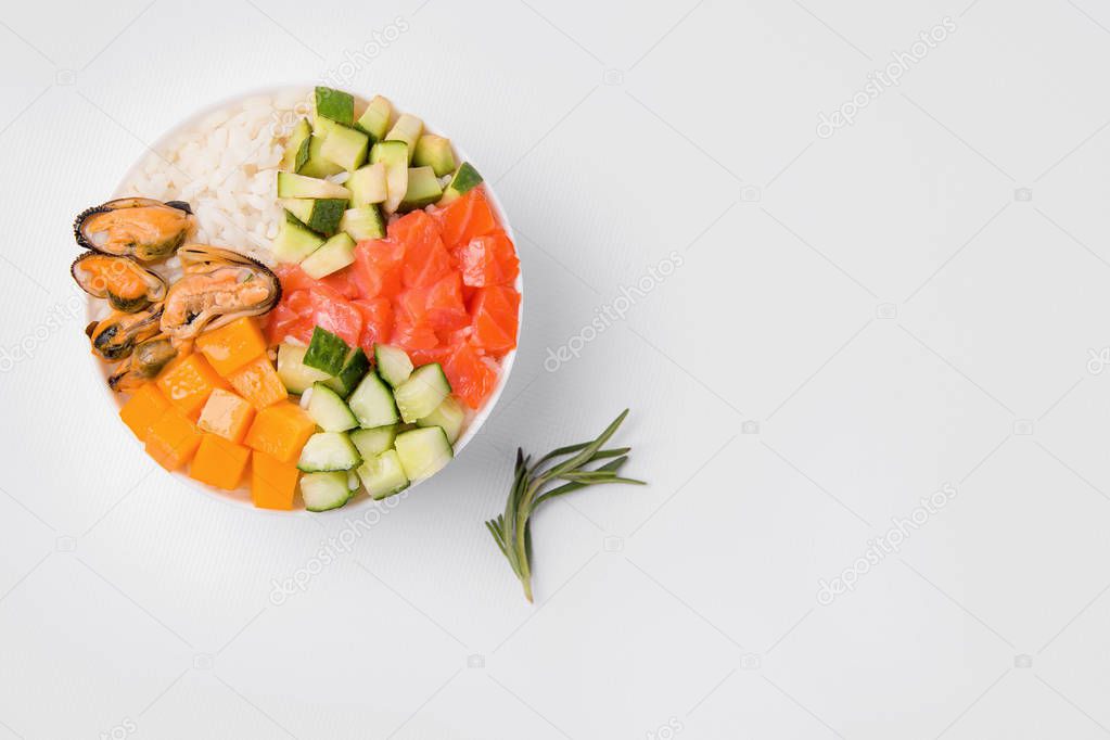 Poke salad with rice, salmon, tuna, avocado, mussels, cucumber and cheese. Hawaiian cuisine. Japanese food. Diced Salad. White background