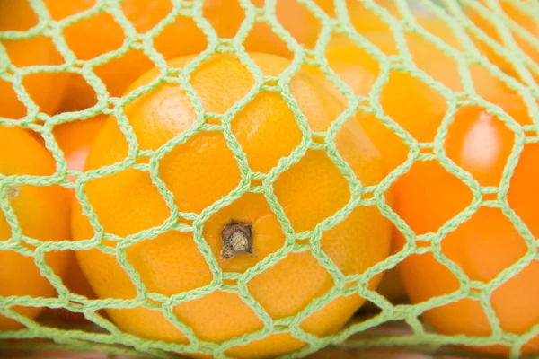 Green string bag with oranges closeup. Ecology. Environmental Protection. ecological package.