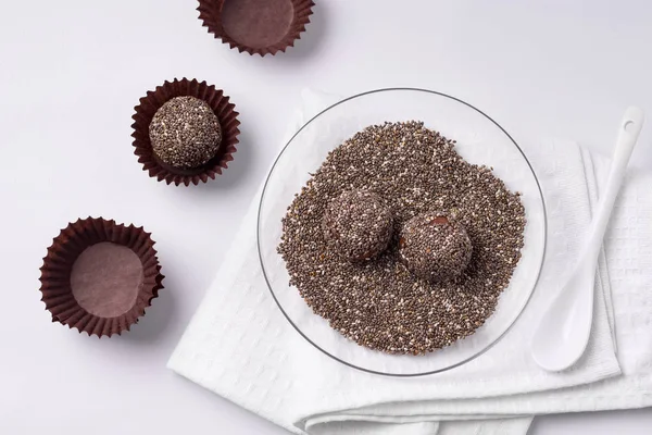 Energy balls sprinkled with chia seeds. Useful sweets from dried fruits on a white background.