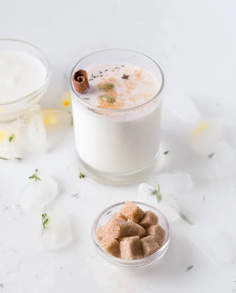 Lassi é uma bebida tradicional indiana ao lado de iogurte e açúcar de cana em um fundo branco . — Fotografia de Stock