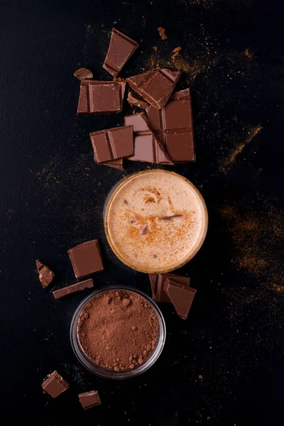 Lassi bebida de chocolate indiano em um fundo preto ao lado de cacau em um fundo preto vista superior — Fotografia de Stock