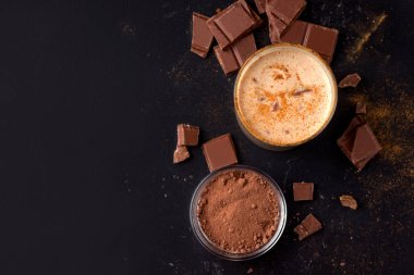 Kakao ve çikolatanın yanında siyah arka planda Lassi çikolatalı soğuk Hint içeceği. Kopyalama alanı olan üst görünüm