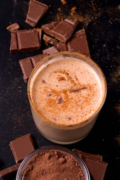 Lassi bebida de chocolate indiano em um fundo preto ao lado de cacau em um close-up preto — Fotografia de Stock