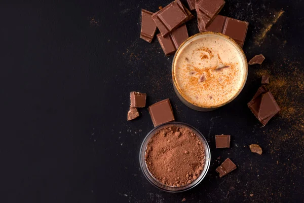 Lassi čokoláda studený indický nápoj na černém pozadí vedle kakaa a čokolády. horní pohled s mezerou pro kopírování — Stock fotografie