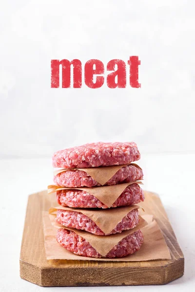 Raw frozen minced meat patties on a wooden board, on a white background. — Stock Photo, Image