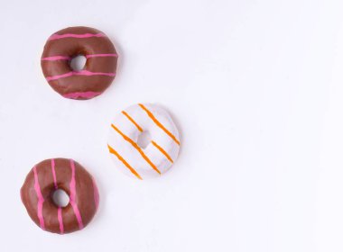 Üç tane çikolatalı çörek ve beyaz bir arka planda vanilya jöleli mesaj için yer var.