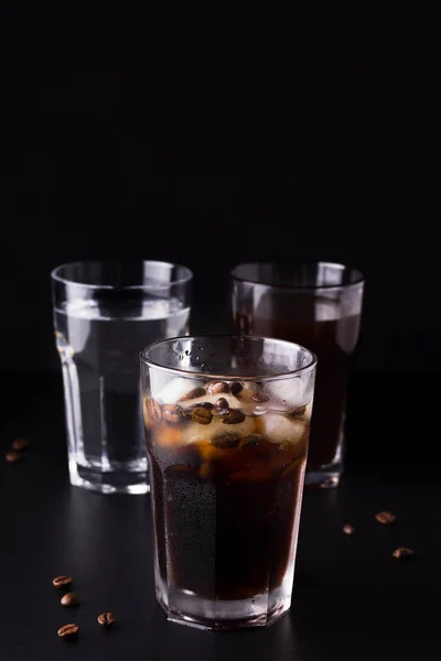 Παγωμένο καφέ σε μαύρο φόντο δίπλα σε κόκκους καφέ και συστατικά — Φωτογραφία Αρχείου