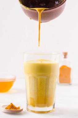 Safranlı altın süt bir kaseden bir bardağa dökülür. beyaz arkaplan.