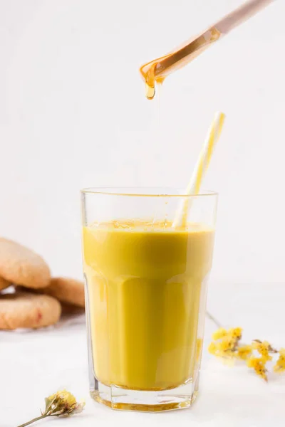 Susu emas di mana madu dituangkan dari sendok kayu — Stok Foto