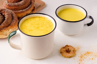 Kahvaltı çörekleri ve elma cipsinin yanında altın süt iç..