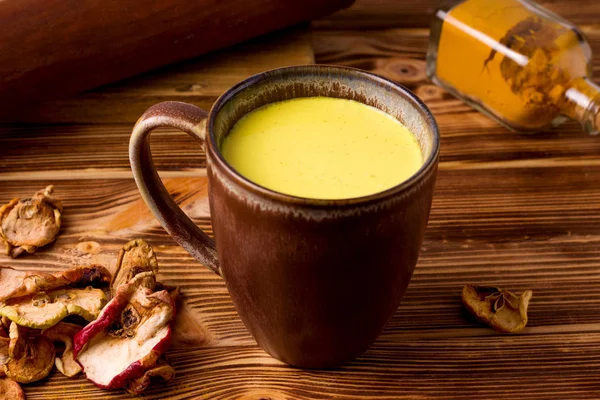 India minum susu emas dengan latar belakang kayu di samping keripik apel buah. rustic — Stok Foto