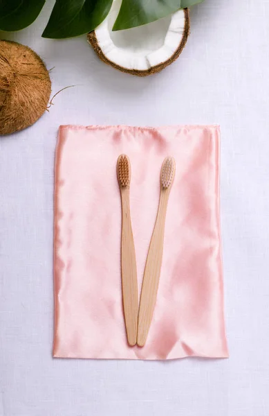 Két bambusz fogkefe rózsaszín ruhán. Zéró hulladék fürdő tartozékok — Stock Fotó